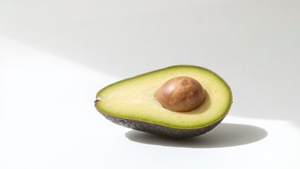 A single ripe avocado, sliced in half, revealing its creamy green flesh and seed, placed on a pure white background.