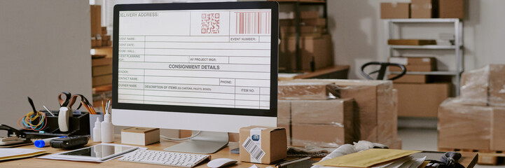Close-up of computer monitor showing shipping label in busy office environment with various...