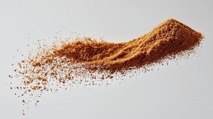A mound of finely ground brown spice cascading downwards against a plain background, highlighting texture