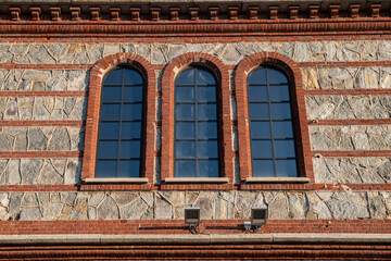 Obraz premium detail of the project and recovery of a historic post-industrial building with facade elements of brick and stone, the windows cite modern triple lancet windows with arches and brick frames.