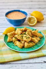 crispy fried fish bites served with a spicy remoulade dipping sauce on a green plate