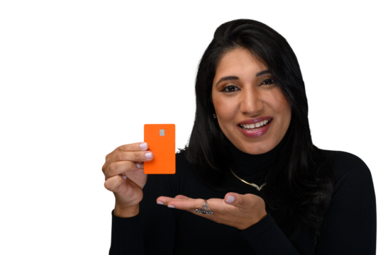 Woman holds an orange credit card and smiles positively looking at the camera.
