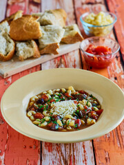 vegetable beef soup topped with parmesan cheese served with bread