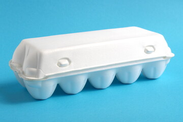 White plastic egg container stands on a blue background.