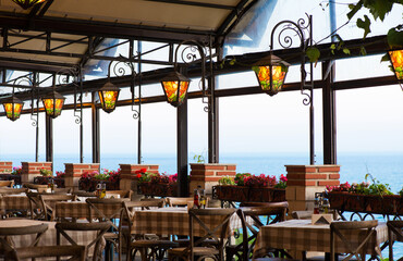 Exterior of a restaurant and terrace by the sea with beautiful colorfull glass lanterns and tables prepared for an event - selective focus