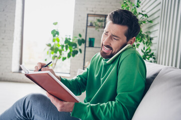 Energetic man multitasking with a phone call and writing during daylight in a casual home setting