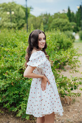 Fototapeta premium Beautiful brunette woman in summer dress walking in the park