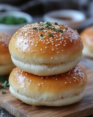 Golden burger buns stacked high with sesame seeds and parsley on a wooden board close up delicious food photography