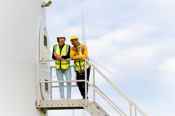 Two engineers discussing maintenance on a wind turbine platform, contributing to sustainable energy production