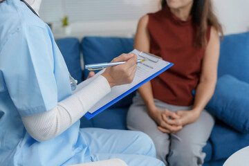 Female doctor taking notes while interviewing patient at home