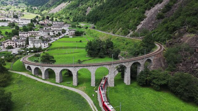 Aerial view of a Bernina Express train crossing the Brusio spiral viaduct of Rhaetian Railway, Grisons canton, Switzerland