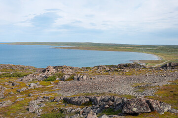 Barents Sea coast, rocky tundra with piles of stones in the foreground. Rybachy Peninsula, Murmansk region, Russia