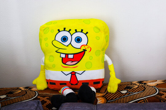 Drogobith, Ukraine, - February  17, 2025: Soft toy of the cartoon character SpongeBob on the back of the sofa in the children's room on the background of a white wall. Cheerful plush SpongeBob SquareP