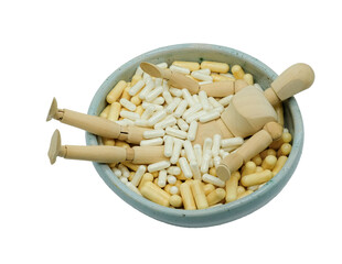 Wooden manikin drowning in pills. Bowl of dietary supplement capsules. Nutrition, supplement dependency, doping, holistic fitness.
