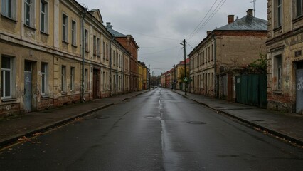 Obraz premium A quiet, empty street with vintage buildings under a cloudy sky.