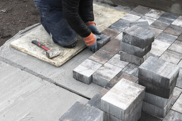 Worker Paving Outdoor Ground with Concrete Bricks and Tools in Action