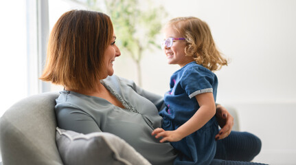 Obraz premium Portrait of girl smiling at camera with her mother at home