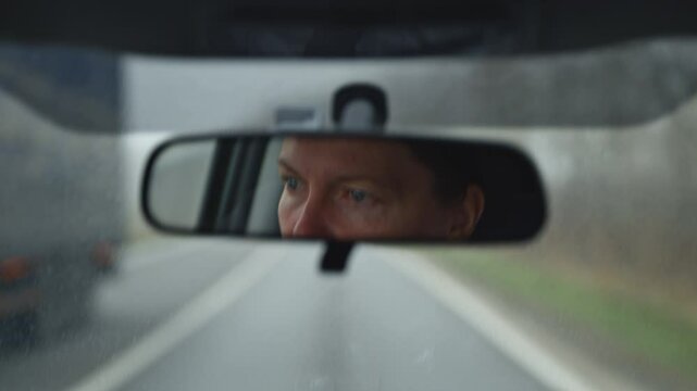 Female driver face at car rear view mirror on a rainy day, 4K