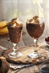 Two cups of healthy chia chocolate pudding with fresh bananas