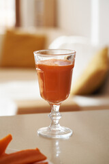 A glass of fresh carrot juice on a kitchen counter