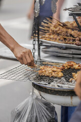 man hand hold grilled chicken shish kebab on the grill day time asian style cheap street food