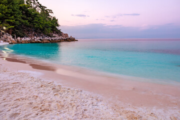 A beautiful beach with a blue ocean and a rocky shore