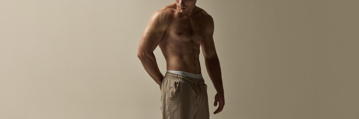 Banner. Bare-chested man standing with strong posture, head slightly lowered, muscles defined,...