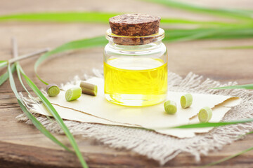 Lemongrass oil or extract  on wooden background with fresh leaves  nearby, copy space, natural medicine, natural hair and skin treatment, aromatherapy concept
