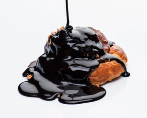 Croissant topped with rich chocolate sauce melting on a white background