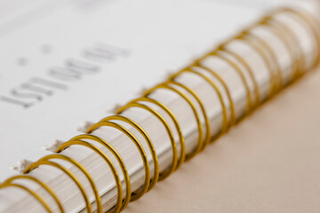 Close-up of a spiral-bound notebook with "To Do List" partially visible, featuring gold rings and white pages for planning and organization.