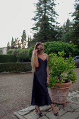 Elegant Woman in a Black Dress with Sunglasses in a Garden
