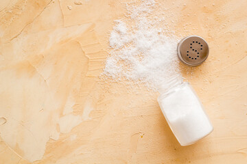 Glass salt shaker and pile of spilled salt, top view. Cooking concept