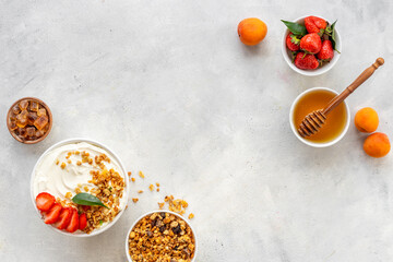 Bowl with yogurt and oatmeal served with honey and strawberry, top view