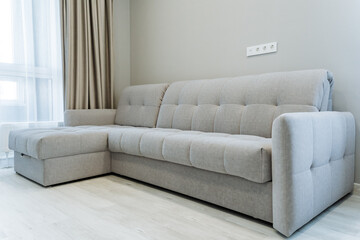 In a cozy living room, a large sectional couch is comfortably positioned next to a window, allowing natural light to brighten up the space, perfect for relaxation and leisure activities