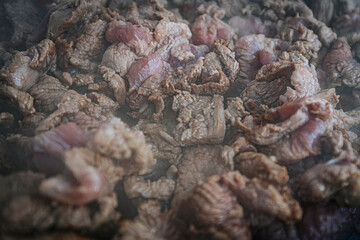 Steaming beef slices simmer in a bubbling broth, releasing rich flavors as they cook. The tender meat absorbs the liquid, creating a delicious dish in progress.