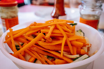 A close-up of a bowl filled with freshly chopped carrots, broccoli, and bamboo shoots. The vibrant orange and green colors highlight the fresh ingredients, ready for cooking or serving.