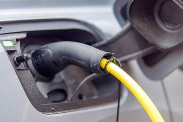 Electric vehicle charging at public station during the day in an urban area