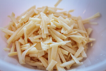 A close-up of sliced bamboo shoots in a white bowl. The fresh, pale yellow pieces are ready for use in cooking, commonly found in Asian cuisine and stir-fry dishes.
