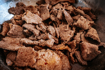 A close-up of cooked beef slices in a pan, showing their texture and slight browning. The meat appears tender and ready for further preparation or serving.