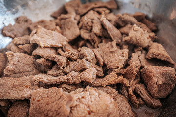 Steaming beef slices simmer in a bubbling broth, releasing rich flavors as they cook. The tender meat absorbs the liquid, creating a delicious dish in progress.