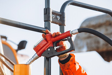 Worker fueling heavy machinery with a gas pump at a construction site during the day