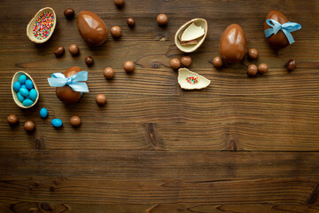 Top view of lots of chocolate Easter eggs with blue ribbon on a wooden background