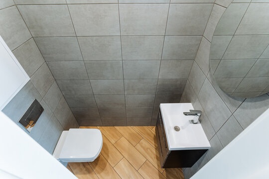 This compact bathroom design maximizes space with essential fixtures like a toilet, sink, and a stylish mirror, ensuring a functional layout that meets modern needs and aesthetics
