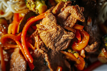 A plate of stir-fried beef with vegetables, including red bell peppers, broccoli, and zucchini, served with noodles in a savory sauce. A delicious and colorful Asian-inspired dish.