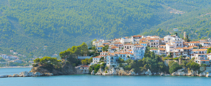 Passing near Skiatos harbor and green wooded island, sailing on blue sea
