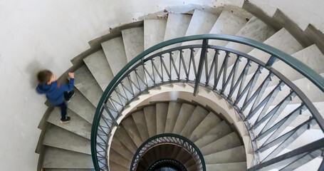 Fototapeta premium One small child going down the spiral stairs