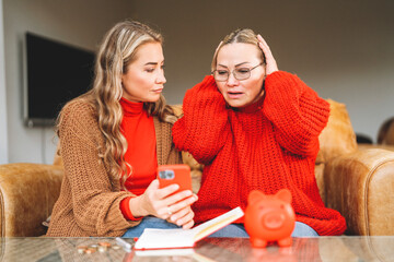 Two women express concern while looking at  smartphone in living room setting