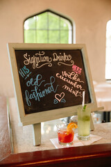 Signature drink menu featuring old fashioned and vodka cucumber mint cocktails at a lively venue