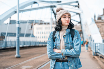 Fototapeta premium Young woman wearing denim on bridge during winter afternoon in urban setting