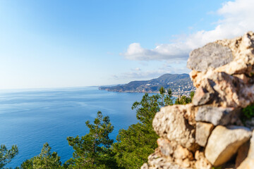 A picturesque coastal scene of Alanya Kleopetra beach and castle with a serene blue sea, lush trees, and distant mountains..